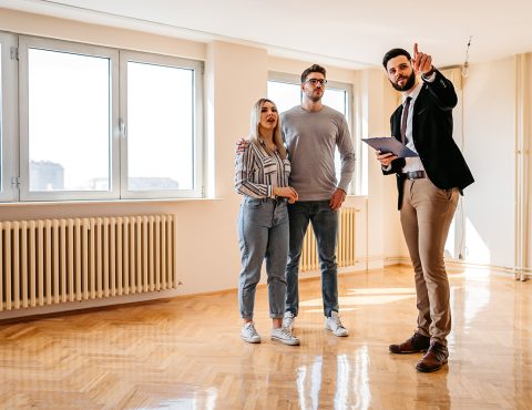 Several people in an empty apartment building. One looks like they are a real estate agent. The other two look like they are viewing the place.