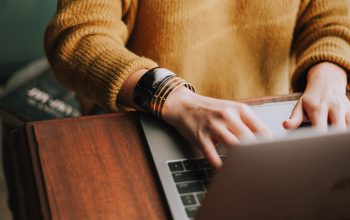 A close up of a persons hands typing on a laptop.