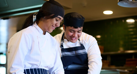 A close up of two student chefs smiling.