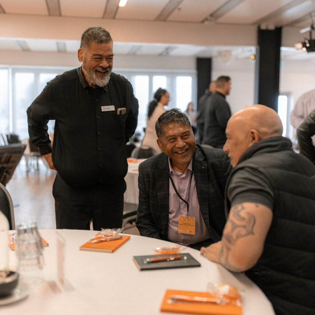 A group of three men at a table, laughing and engaged in conversation.