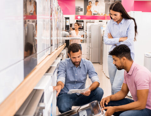 Three people in a white ware shop looking at a instruction booklet.