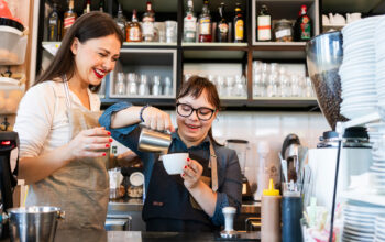 Two people in a coffee shop making coffee.