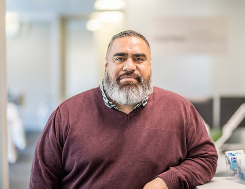 A close up of a person wearing a maroon top.