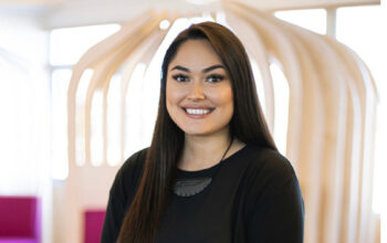 A close up of a person smiling and wearing a black top.