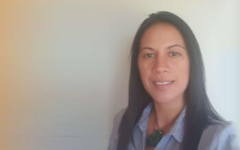 A close up of a person wearing a grey formal jacket. On the right is a graphic representing the values of Ringa Hora.