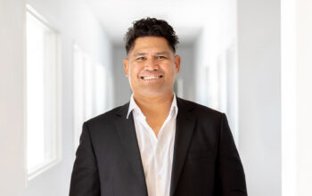 A close up of a person smiling and wearing a suit.