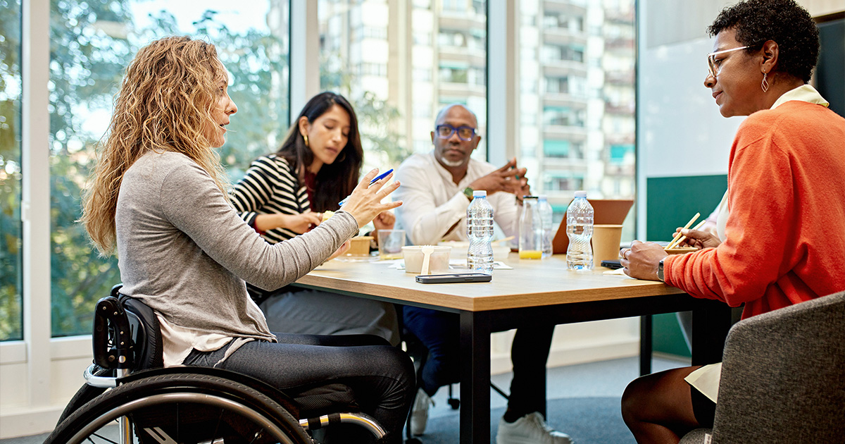 A women in a wheelchair talks to a diverse group of proessionals