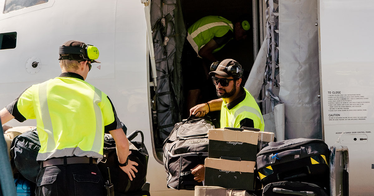 airport crewmembers working together loading cargo