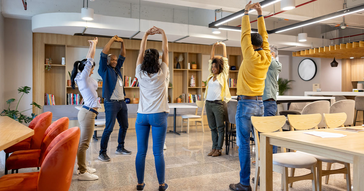 Group of people in an office standing doing stretches